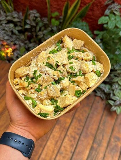 Fettuccine al mascarpone con pollo, parmesano y cilantro en un contenedor de papel kraft